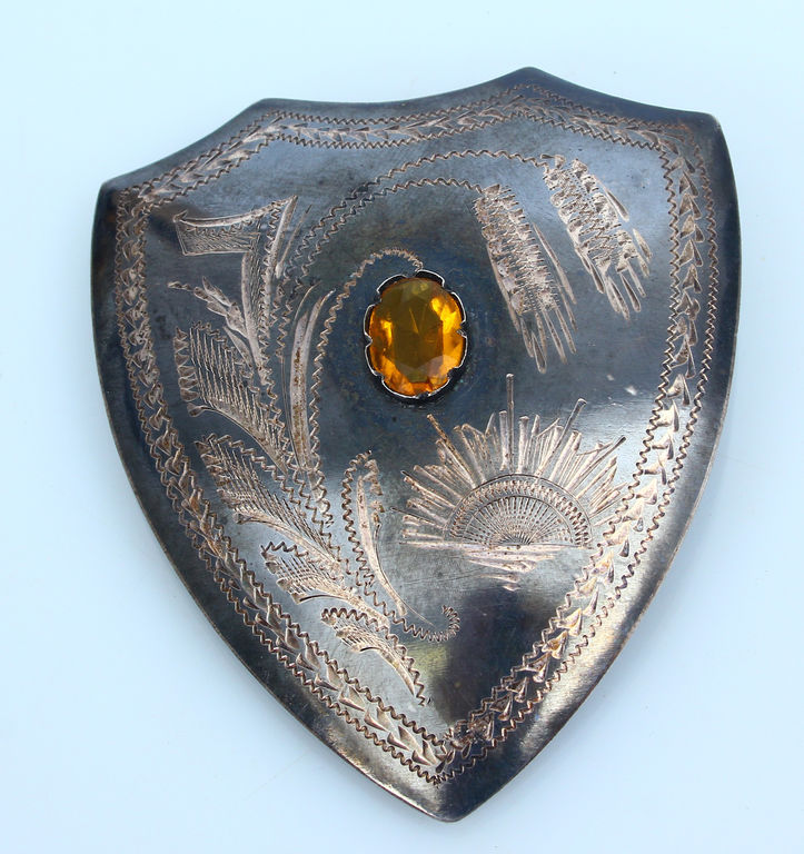 Silver brooch with yellow stone in the shape of a shield