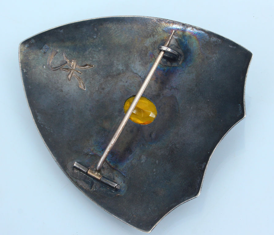 Silver brooch with yellow stone in the shape of a shield