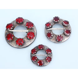3 silver brooches with red stones
