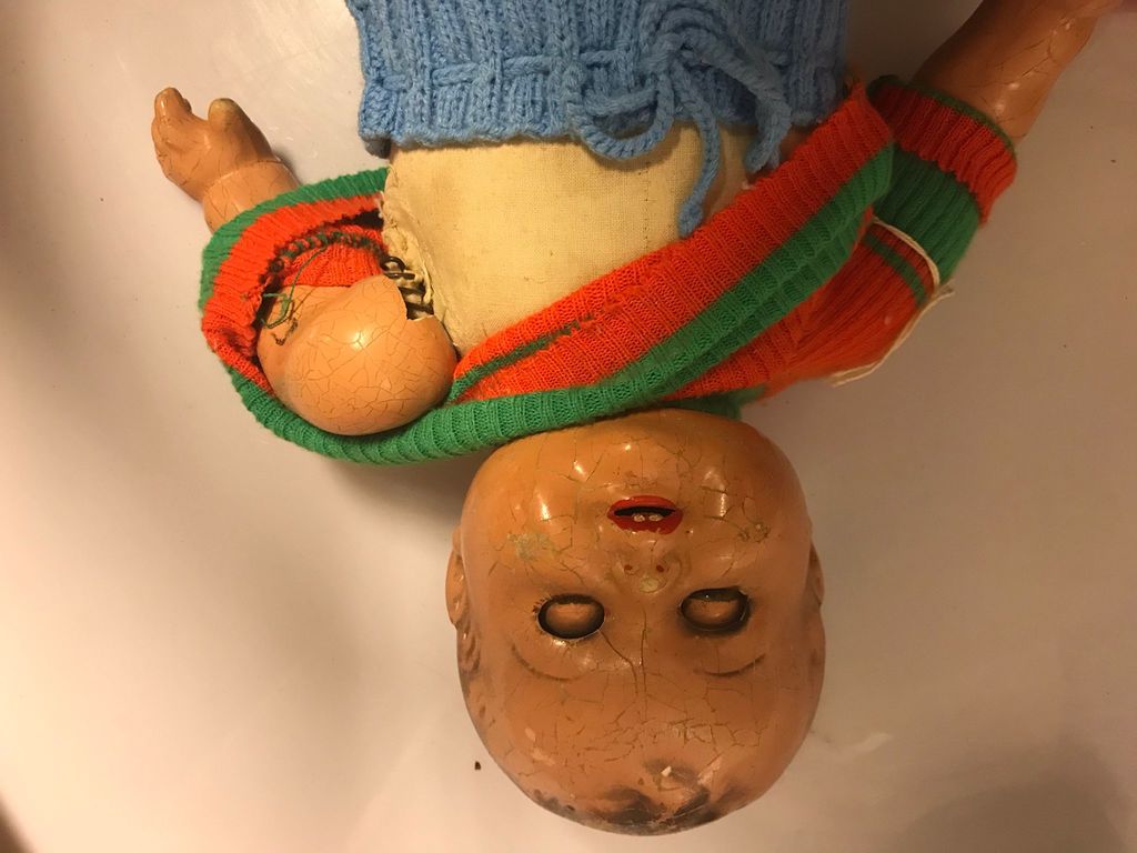 Doll with a porcelain head. The doll has a broken arm