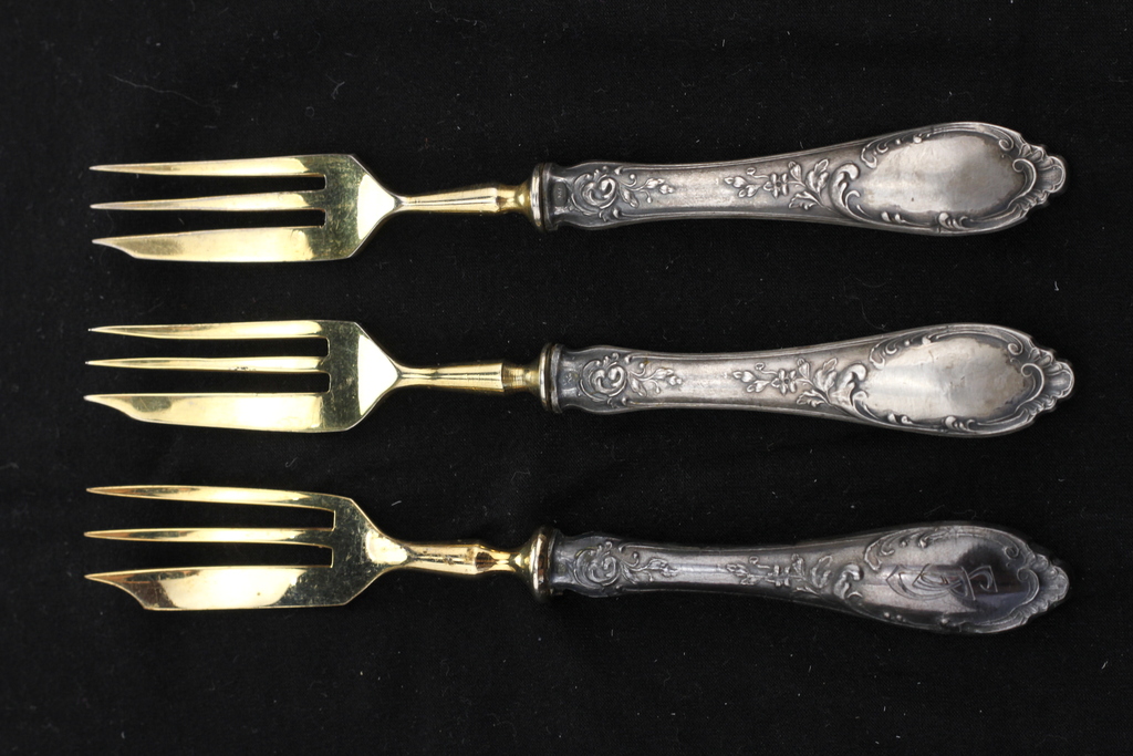 Три позолоченные десертные вилки с серебряными ручками.