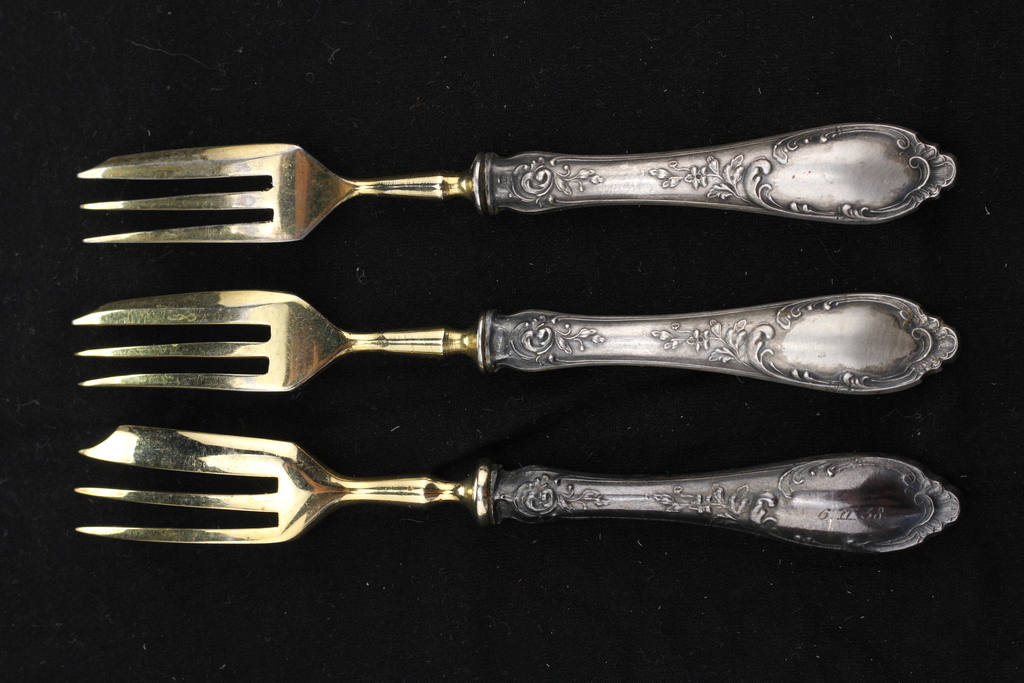 Три позолоченные десертные вилки с серебряными ручками.