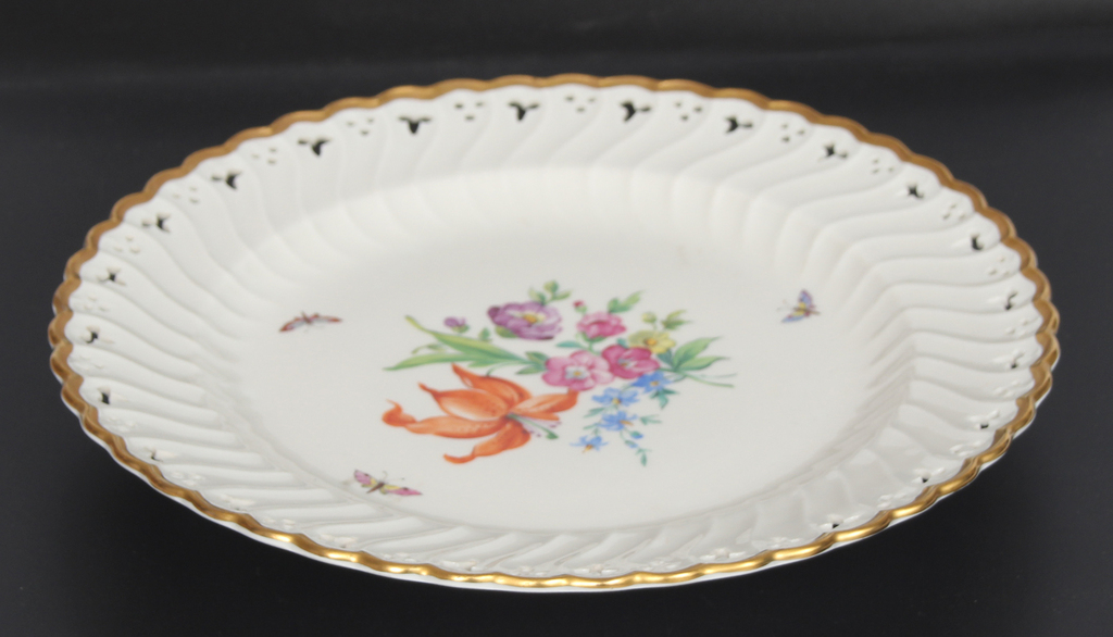 Фарфоровая тарелка с цветочным мотивом и декоративным внешним краем.