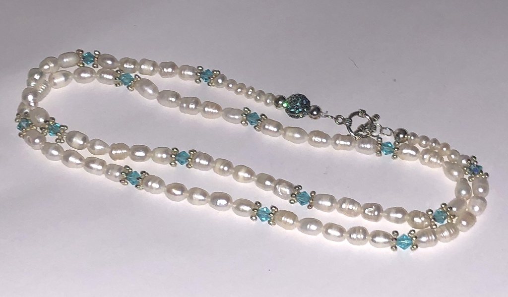 Long white freshwater pearl beads with light blue crystals and other metal elements.