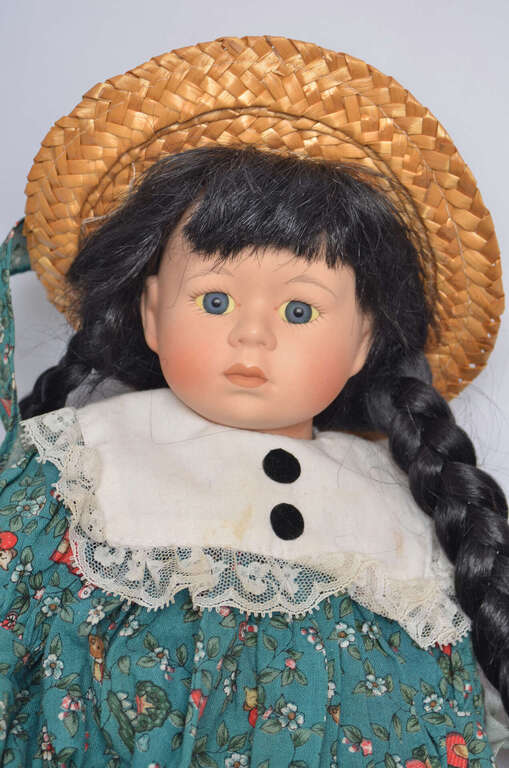 Vintage porcelain doll in a straw hat